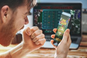 Pria yang memenangkan permainan kasino online saat menggunakan ponsel