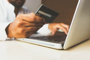 pria yang memegang kartu kredit melakukan pembayaran di komputer